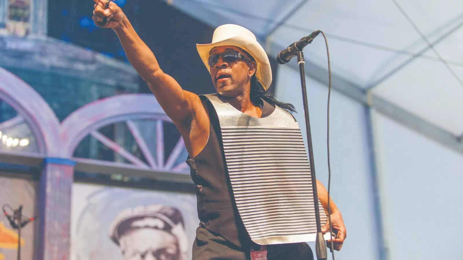 a person with a cowboy hat and sunglasses holding a microphone