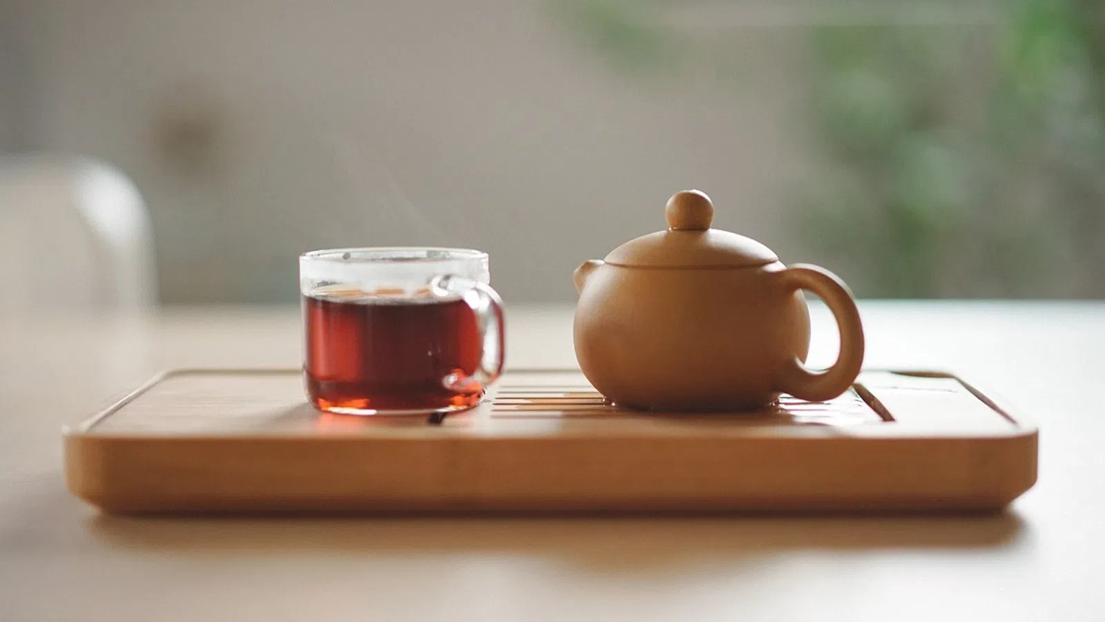 a teapot and a glass of tea on a tray