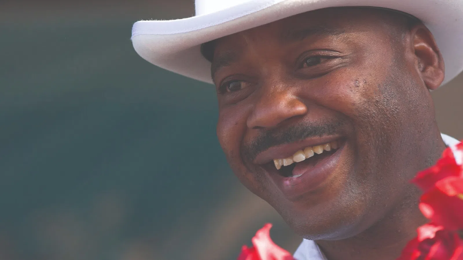 a man wearing a white hat and smiling at the camera