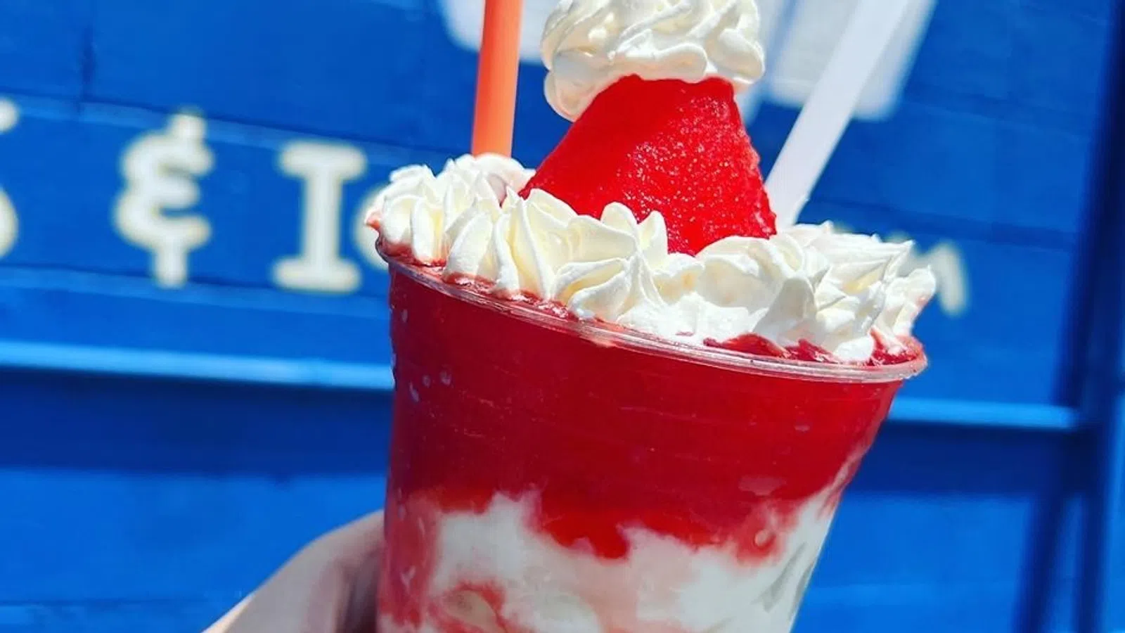 a hand holding a red drink with a straw