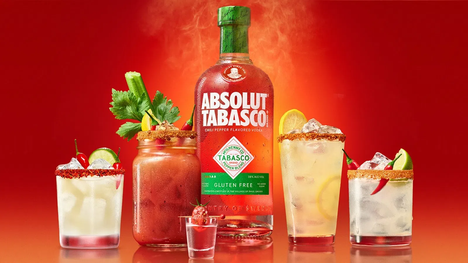 Absolut Tabasco vodka bottle surrounded by four spicy cocktails with garnishes on a red background.