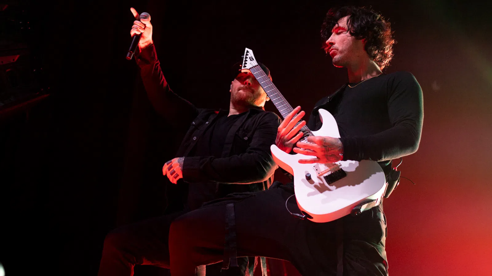 a man playing a guitar next to a man playing a guitar