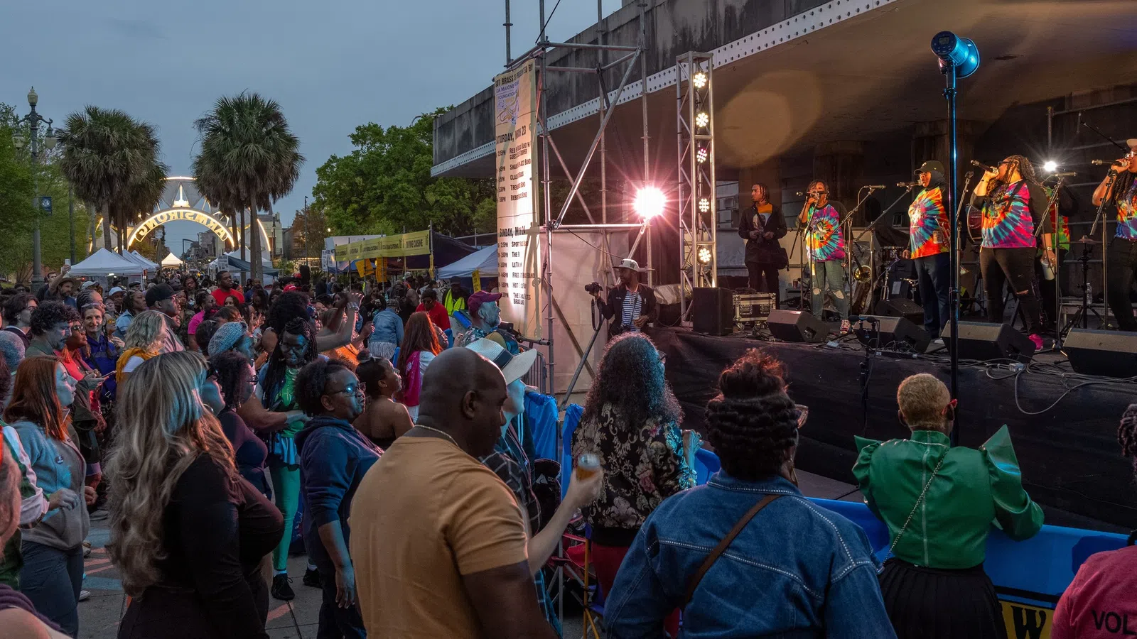 Crowd enjoying live music at a vibrant outdoor festival with performers on stage.