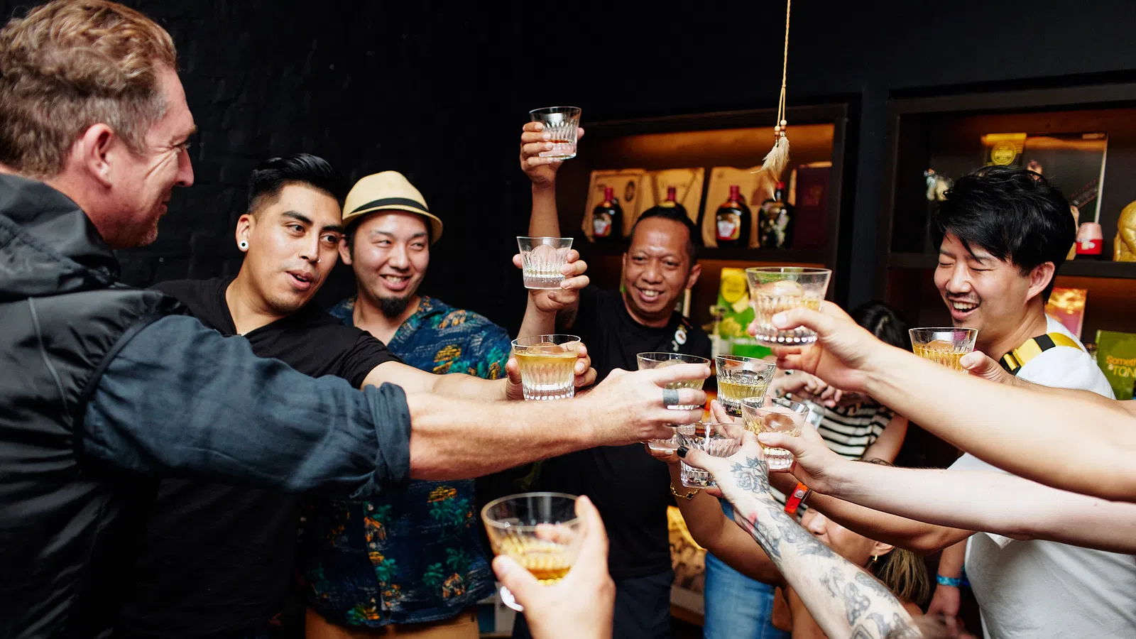 Group of friends raising glasses together in a cheerful toast at a cozy indoor gathering.