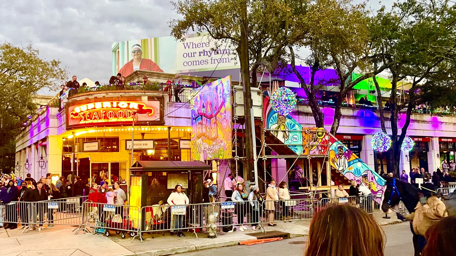 Crowd gathered outside a seafood restaurant decorated with colorful murals and festive lights at dusk.