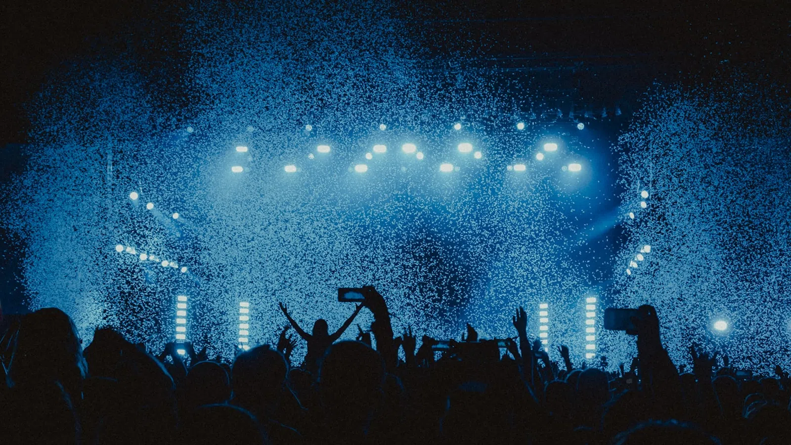 a crowd of people in front of a stage with lights