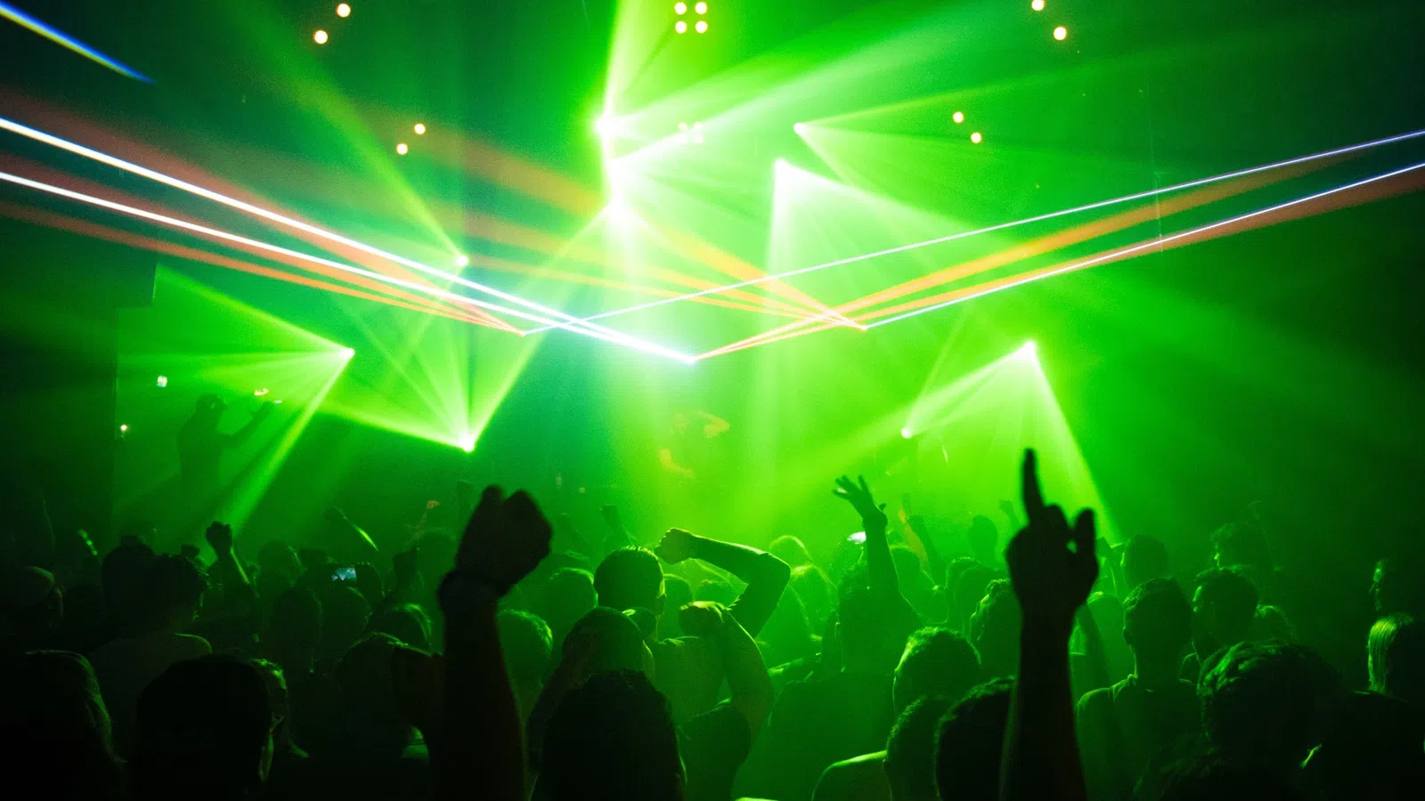 a crowd of people in front of a stage with green lights