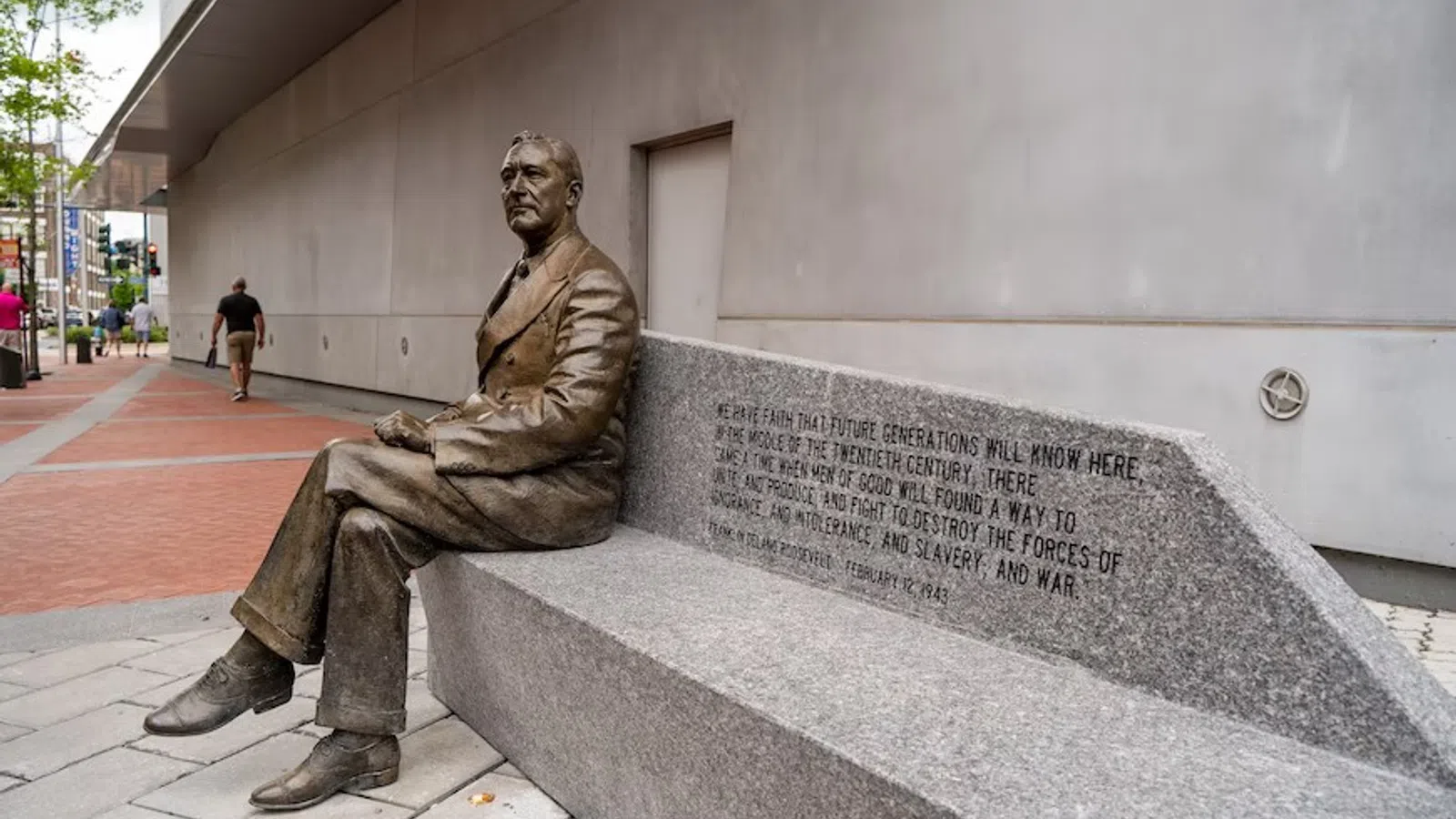 a statue of a man sitting on a stone bench