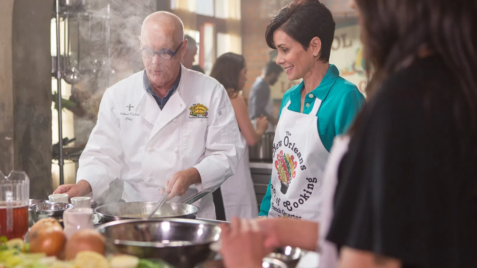 a man and a woman standing next to a table with food