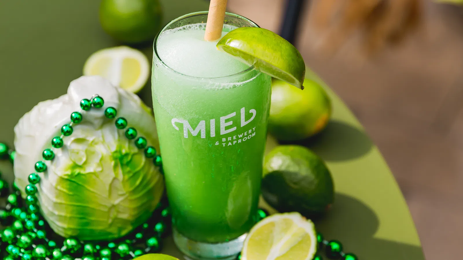 a glass of green liquid with limes and limes