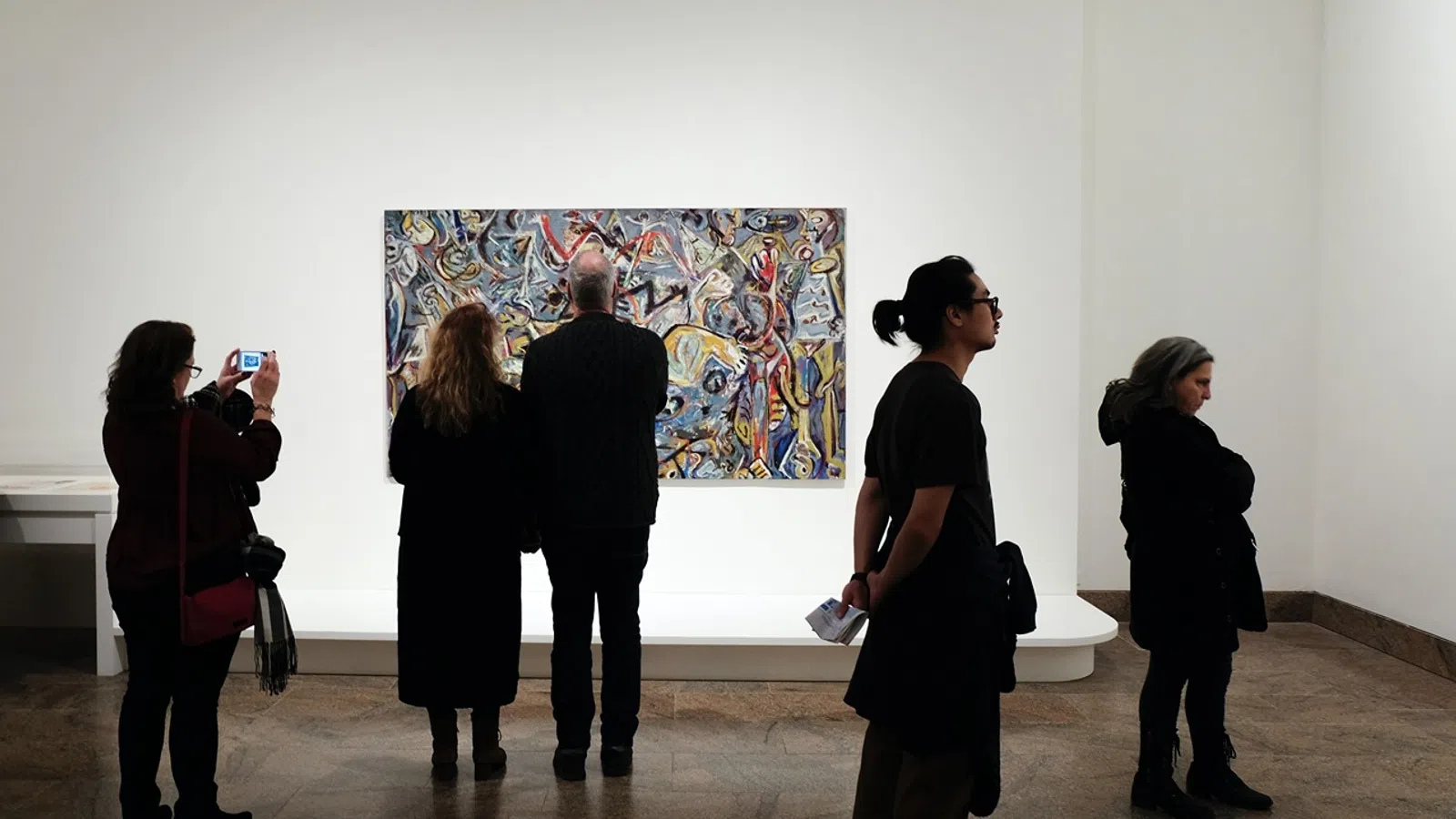 a group of people looking at a painting on a wall