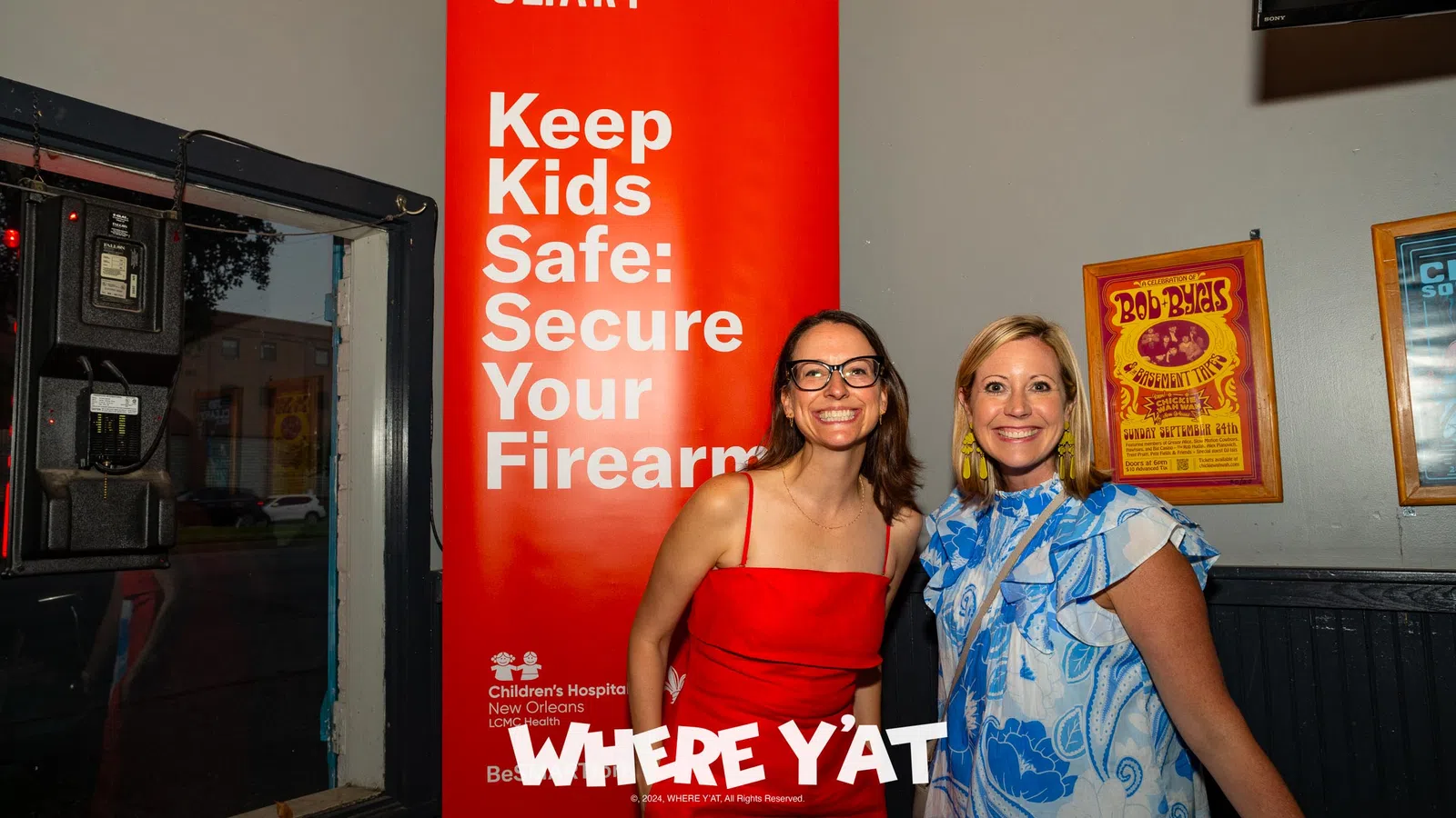 a couple of women posing for a picture in front of a sign