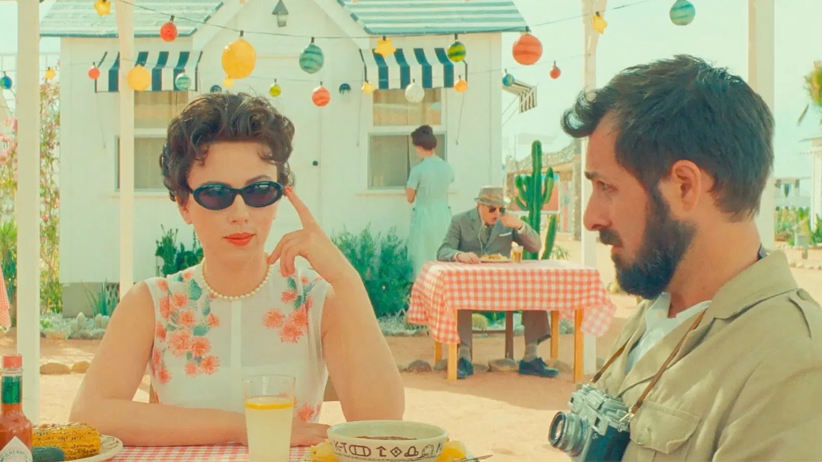 a man and woman sitting at a table with food and drinks