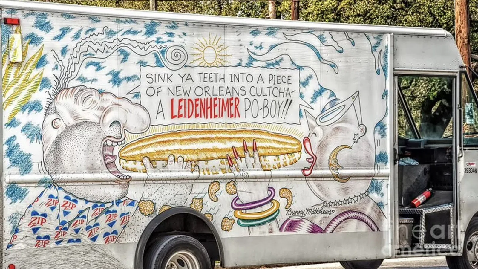Truck mural featuring a man about to eat a large po-boy sandwich with vibrant New Orleans-themed artwork.
