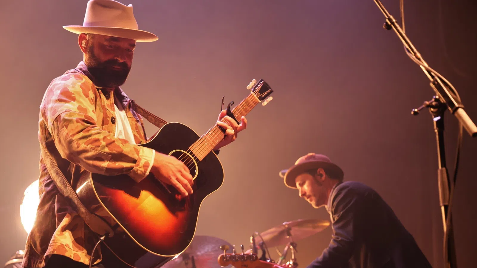 a man playing guitar next to a man playing drums