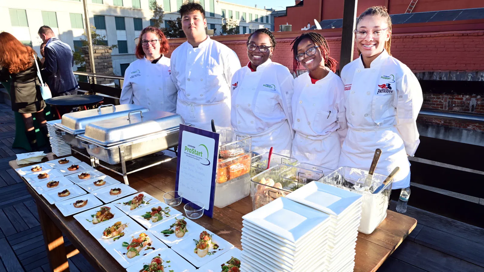 a group of people in white coats standing next to a table with food