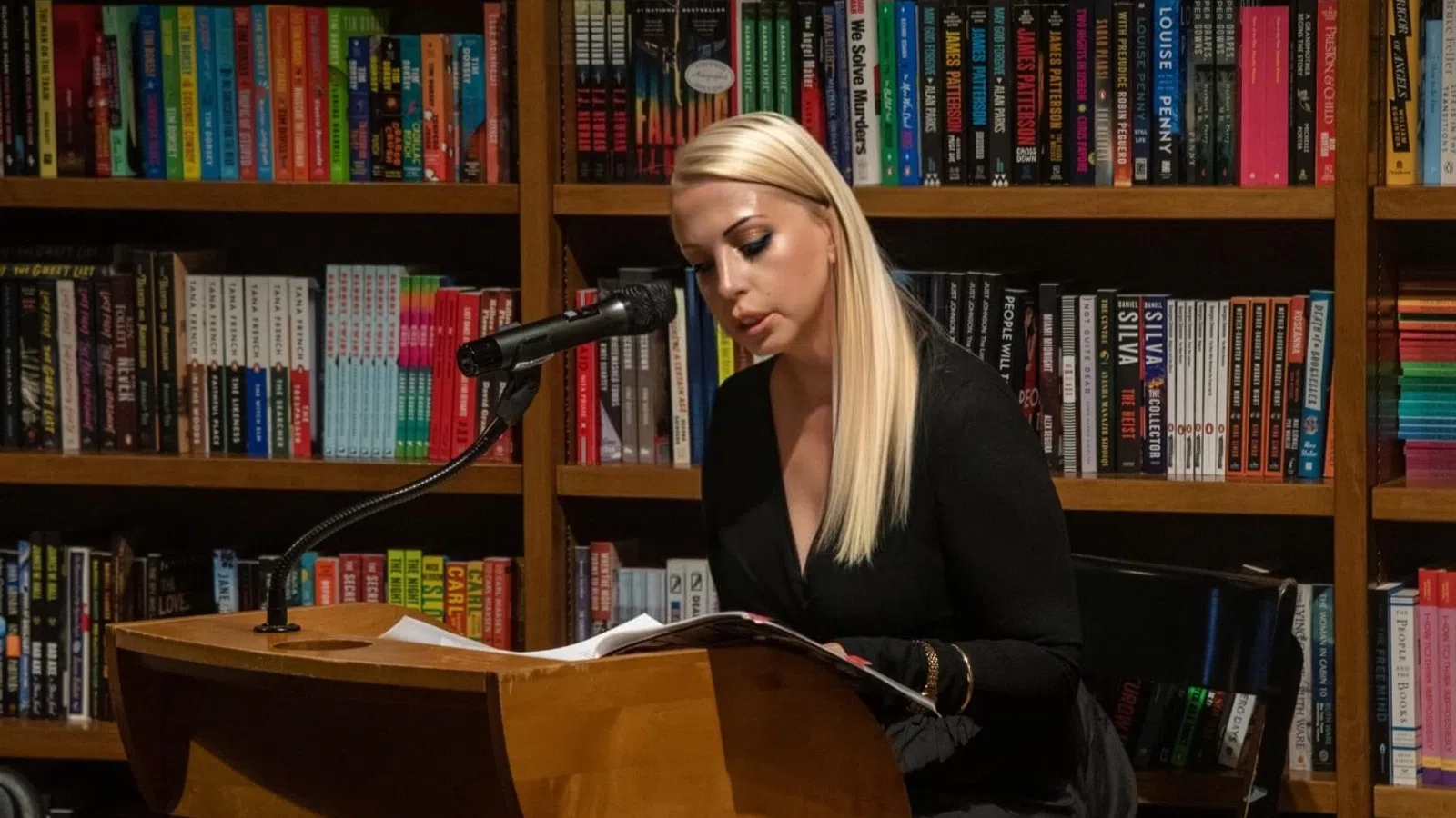 a person sitting at a desk in front of a book shelf
