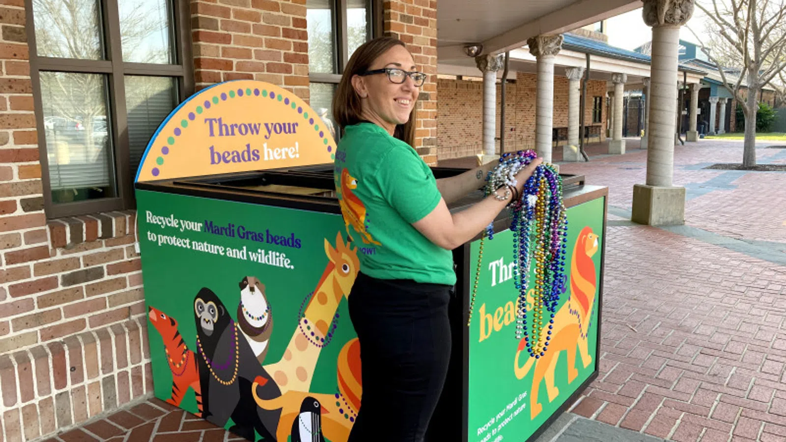 Woman recycling colorful Mardi Gras beads at a decorated collection bin to protect wildlife and nature.