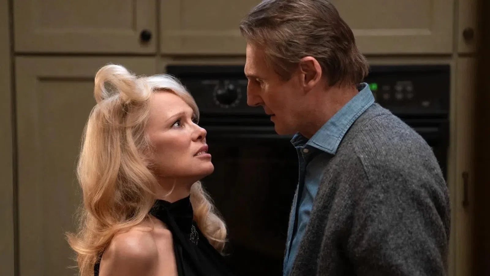 Man and woman in intense conversation in a kitchen, showing emotional tension and close proximity.