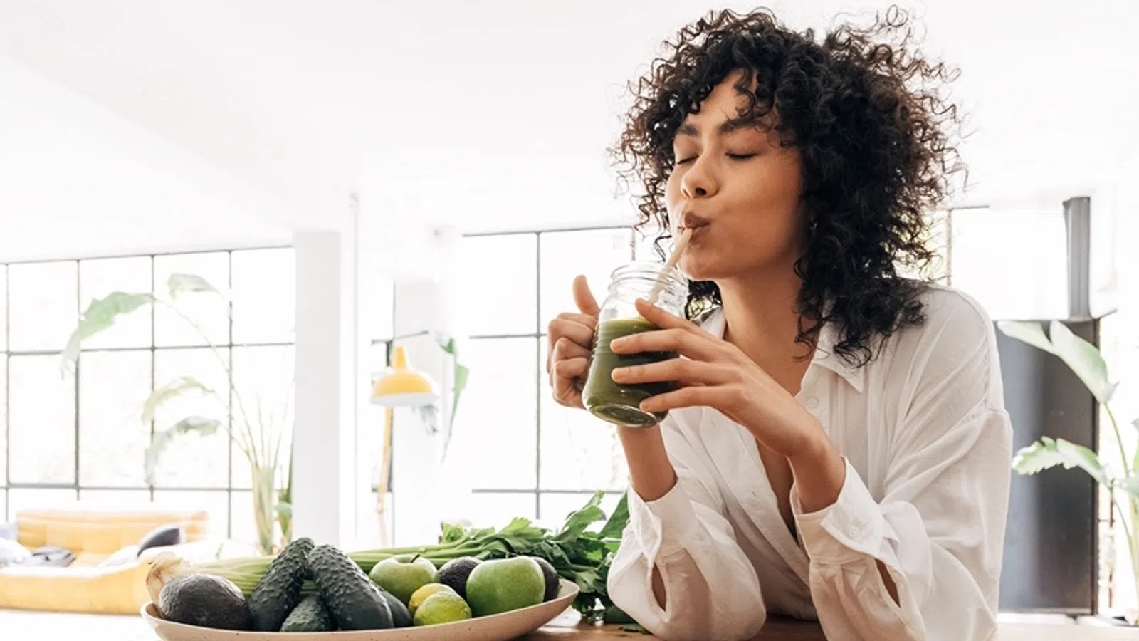 a girl sitting at a table with a bowl of fruit and a bottle of water