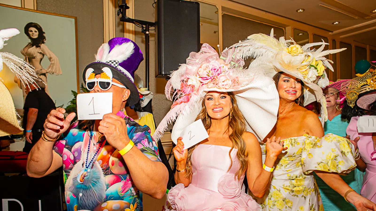 Colorful attendees in extravagant hats at a lively event, showcasing vibrant fashion and fun.