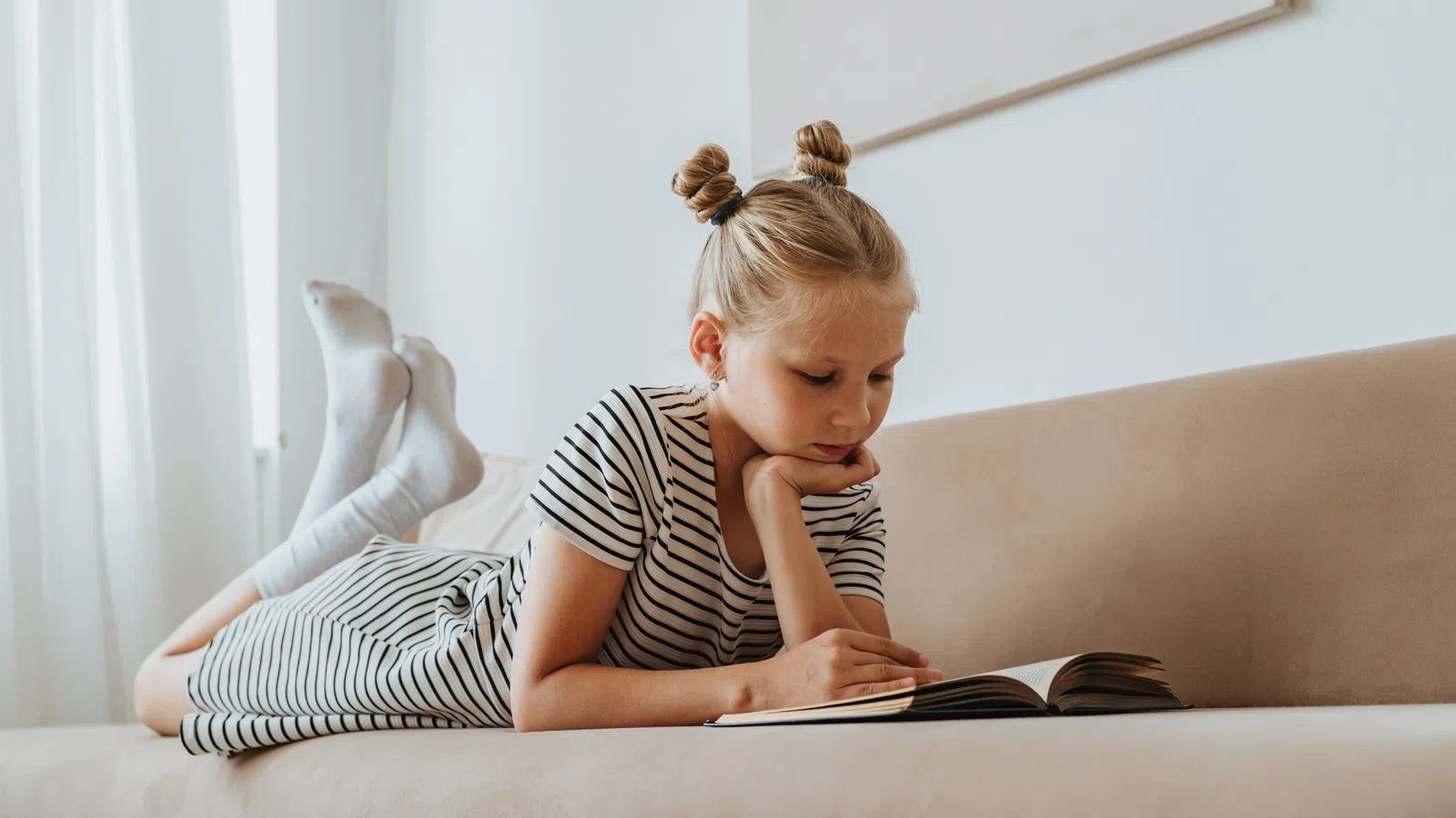 a girl sitting on a couch reading a book