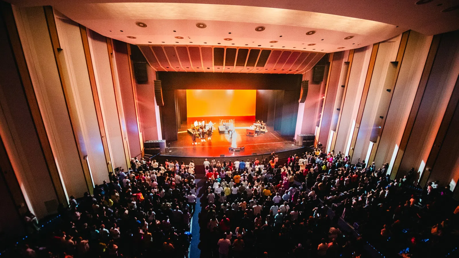 a large group of people in a room with a stage and a large audience