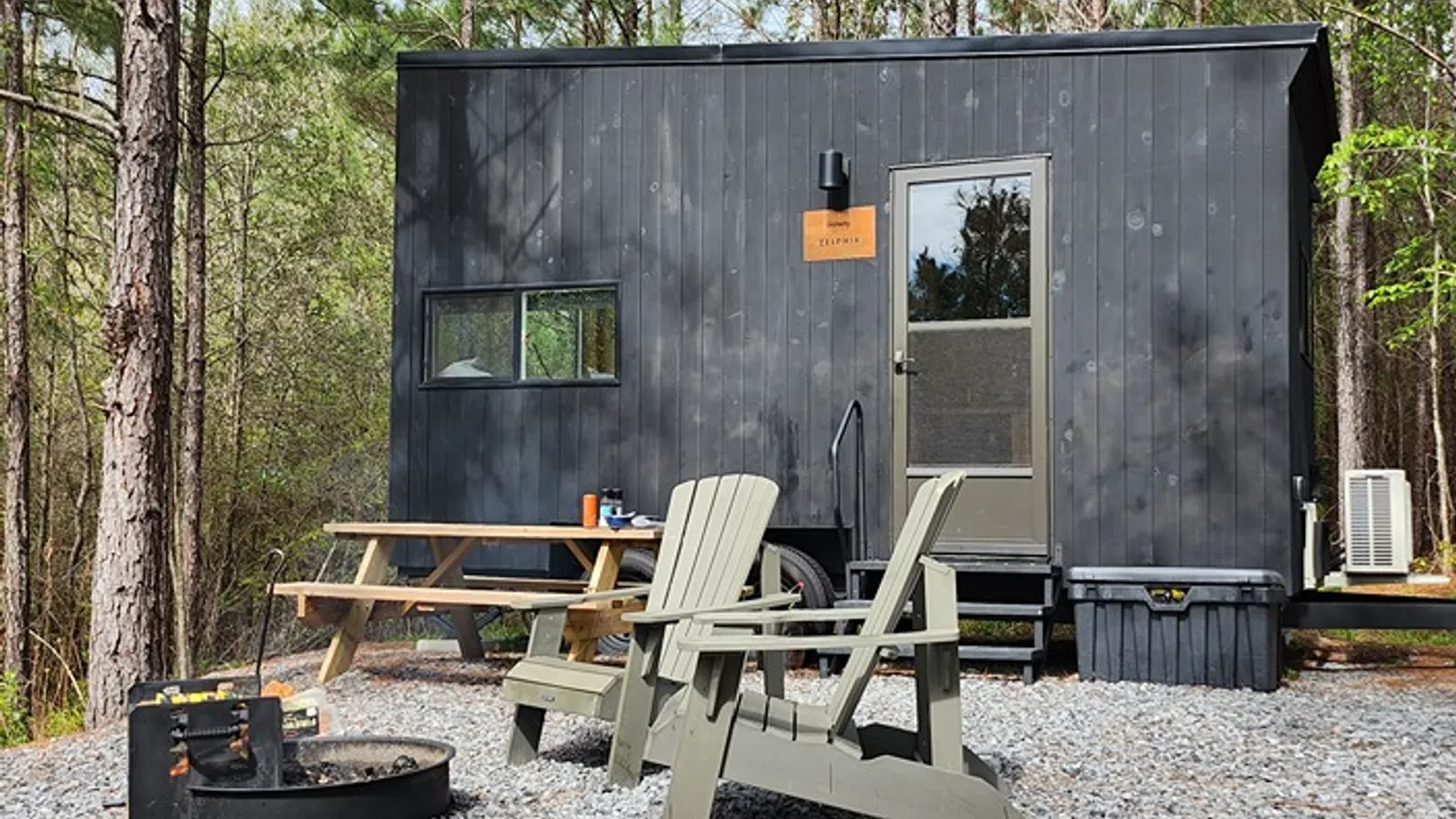 a small cabin with a picnic table and chairs in front of it