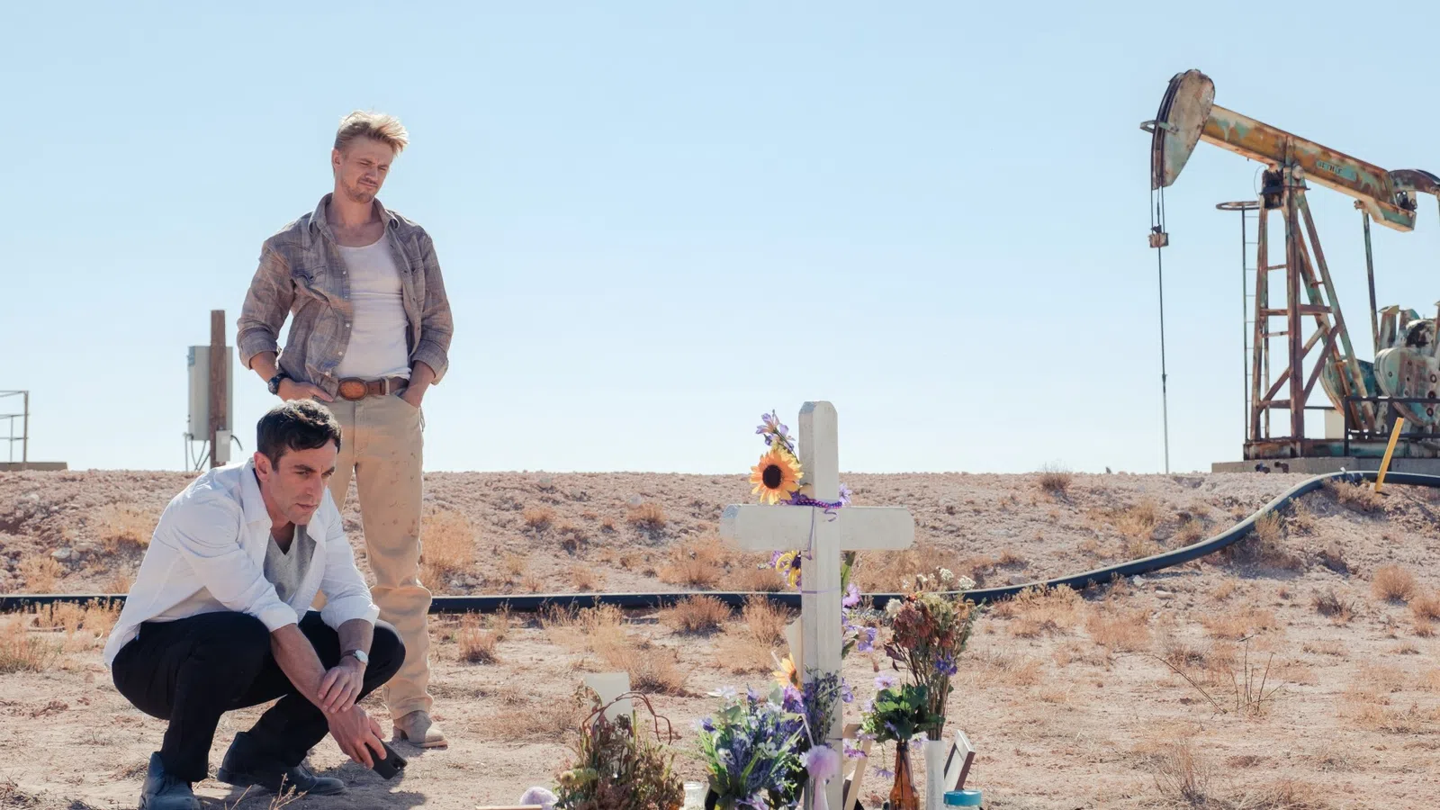 a man and woman kneeling next to a cross with flowers and a cross