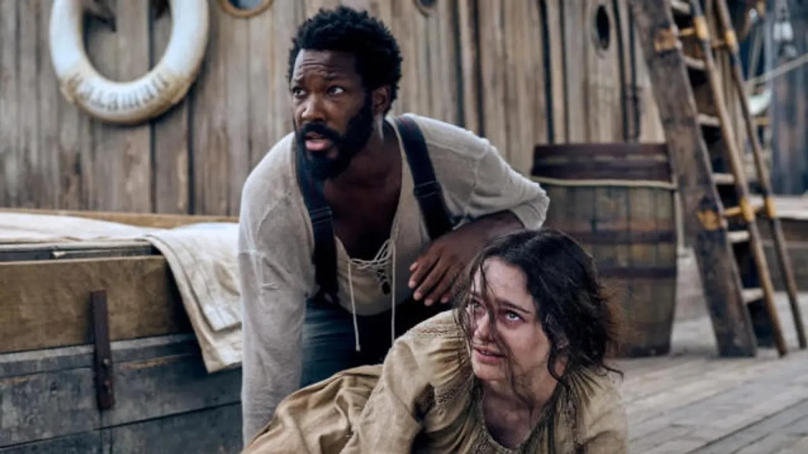 a man sitting on a bed with another man standing behind him