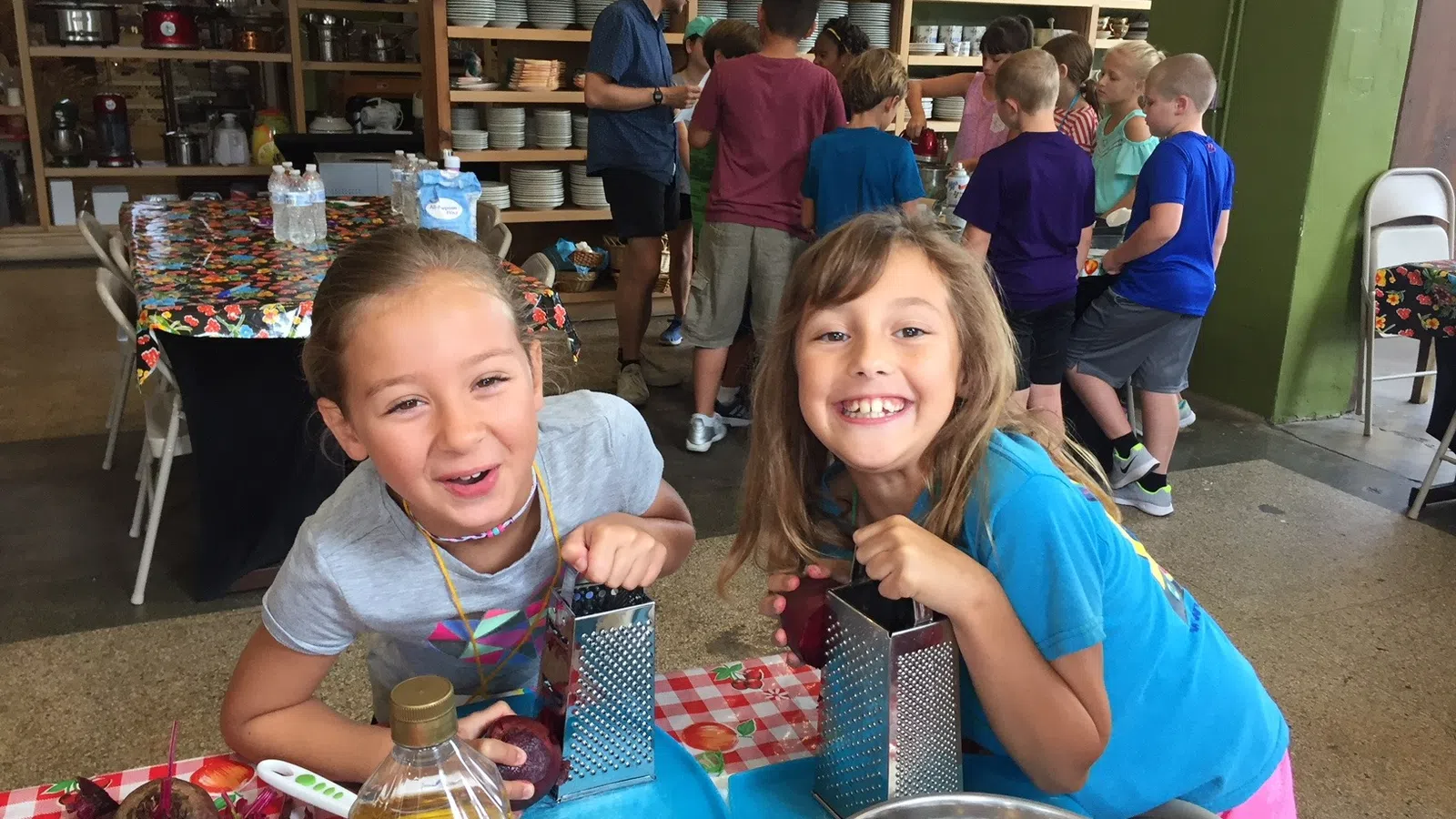 a couple of children sitting at a table with food and drinks