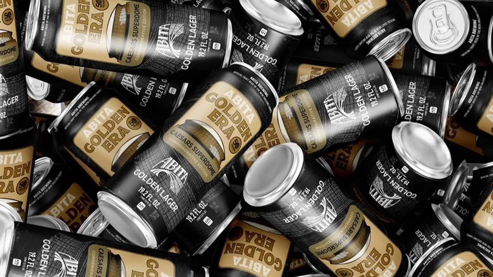 Multiple black and gold Abita Golden Era beer cans scattered in a flat lay arrangement.