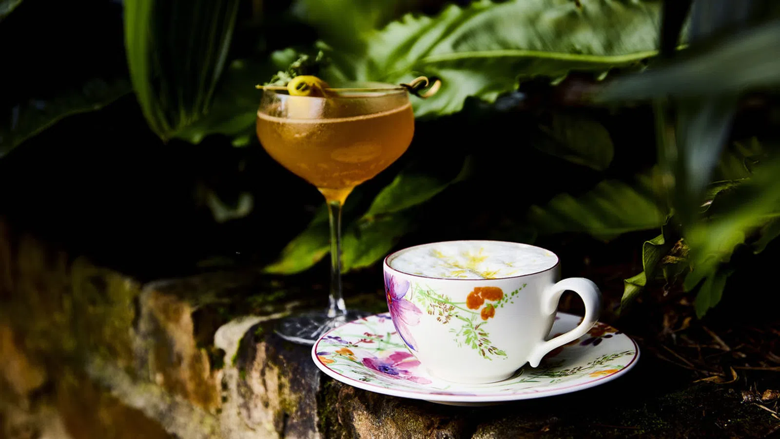 a glass of liquid and a cup of tea on a saucer