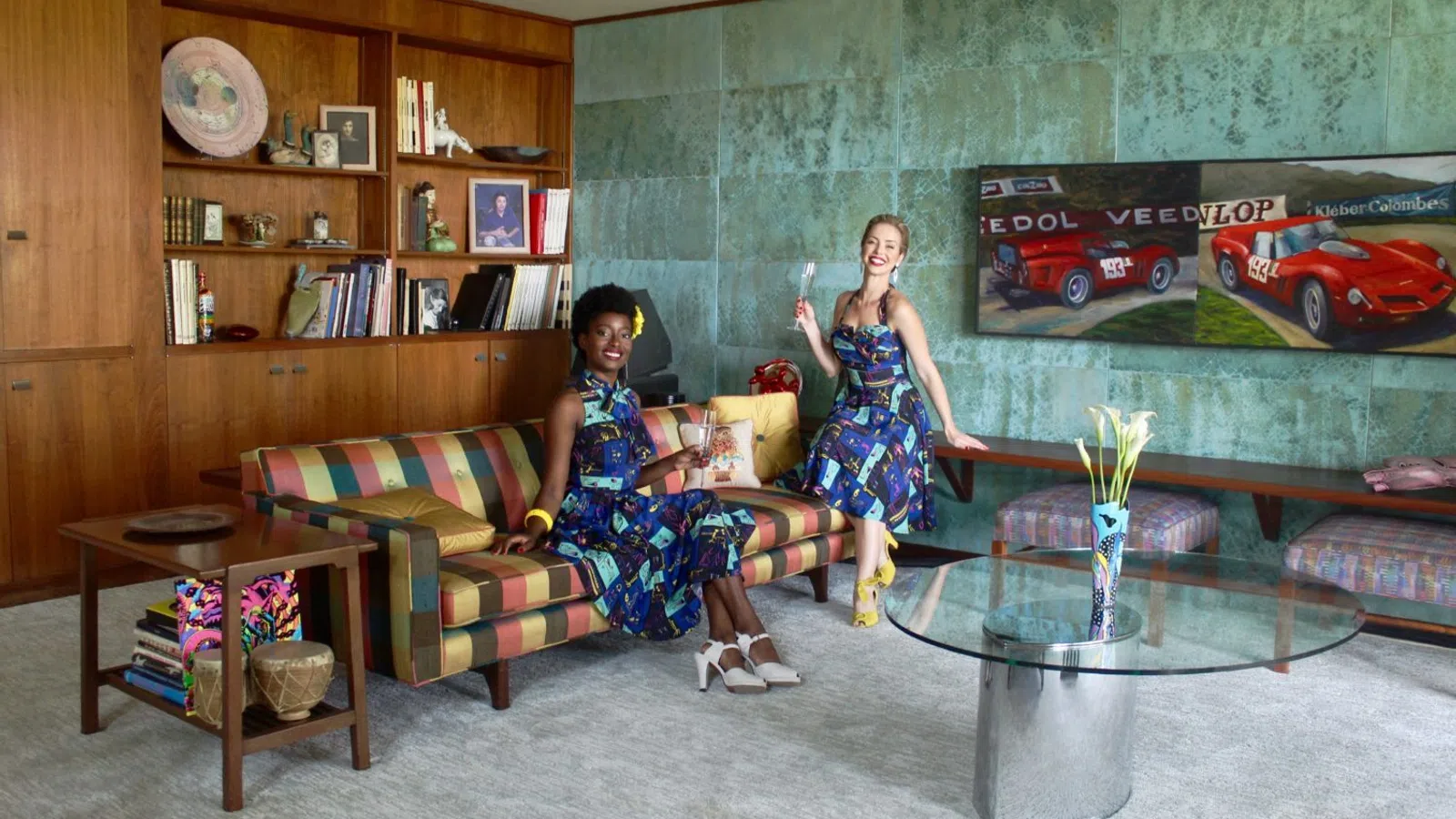 a couple of girls sitting on a couch in a room with a green wall and a table with