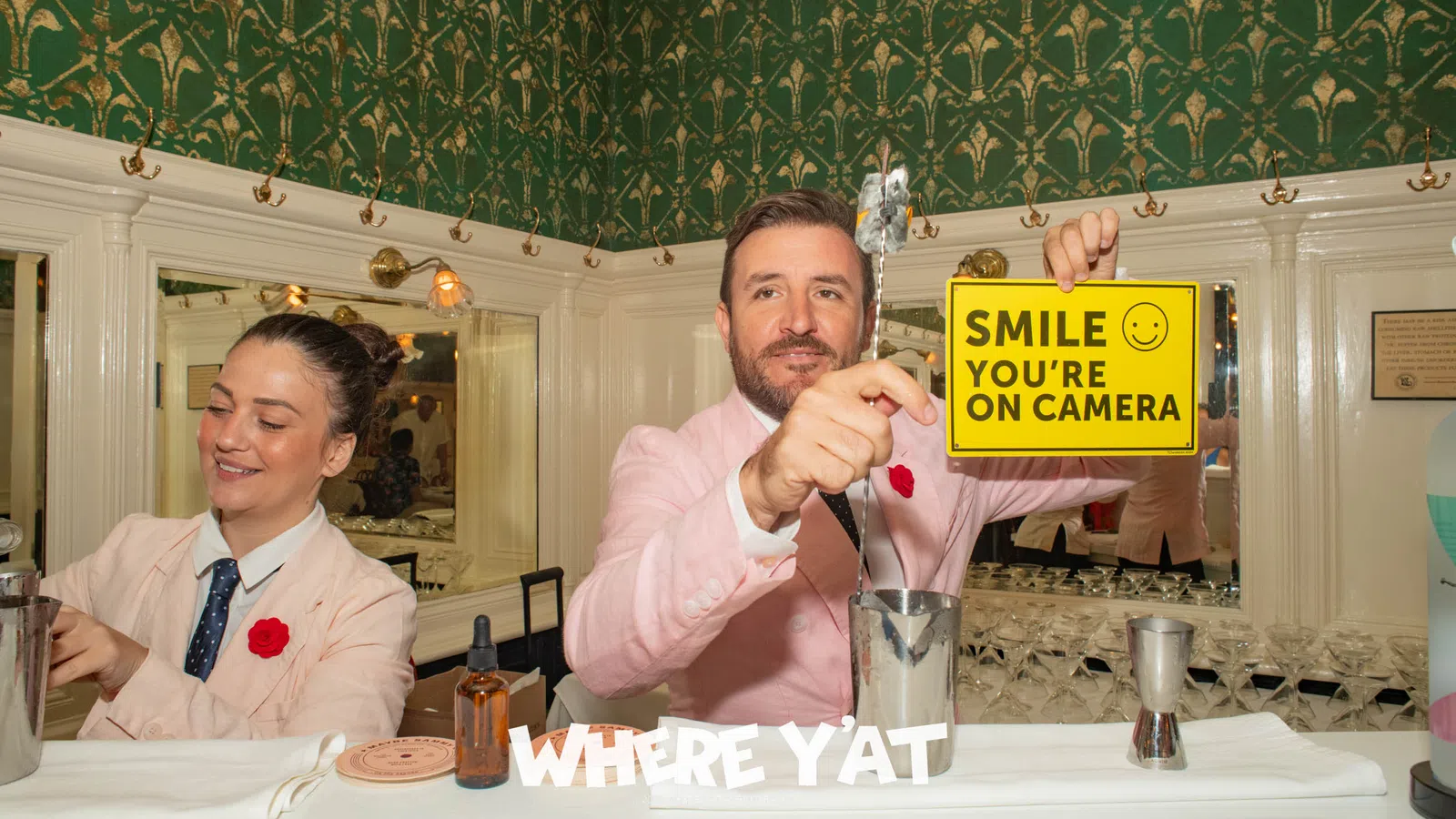 a man and a woman sitting at a table with a sign