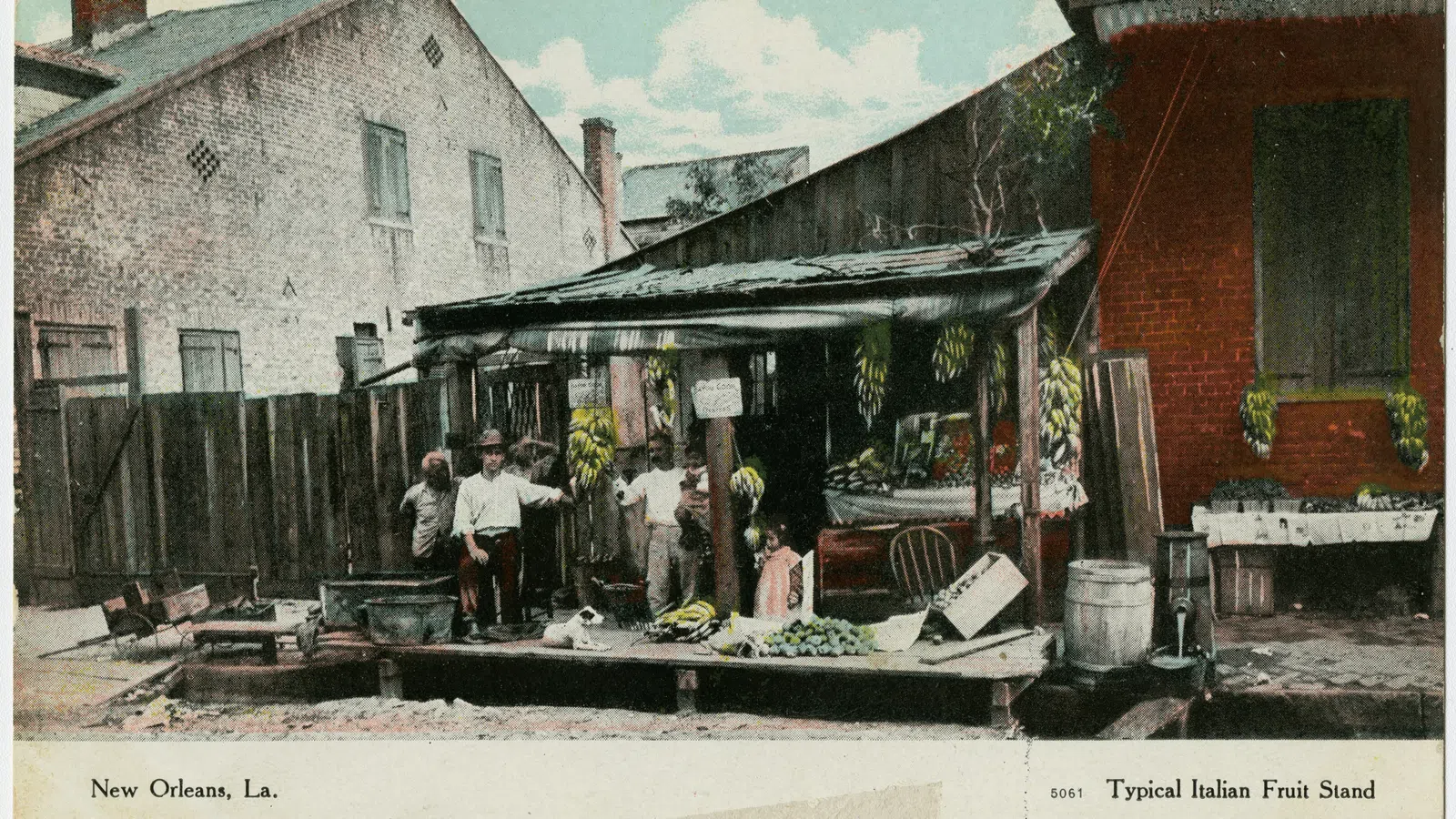 Vintage Italian fruit stand in New Orleans with vendors and fresh produce under wooden shelter.