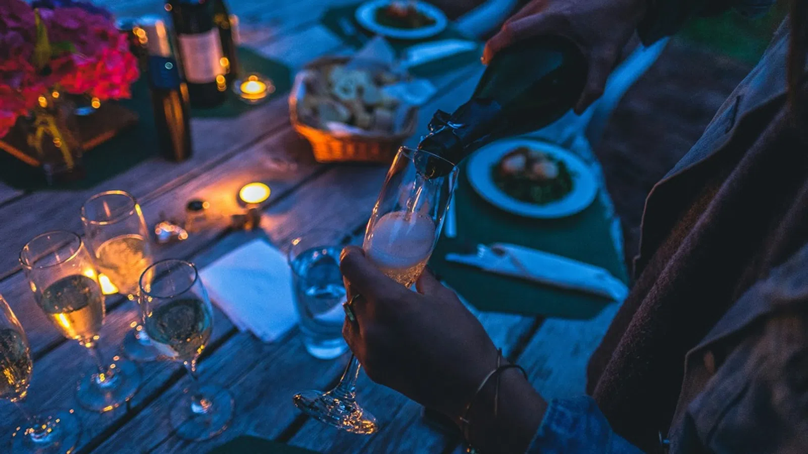 a person pouring wine into glasses