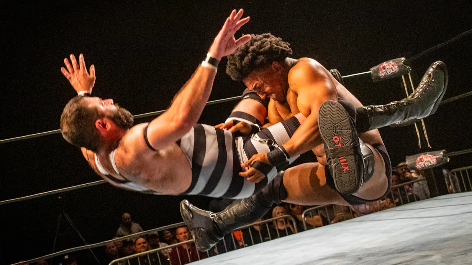 a person kicking another man in the face with a microphone