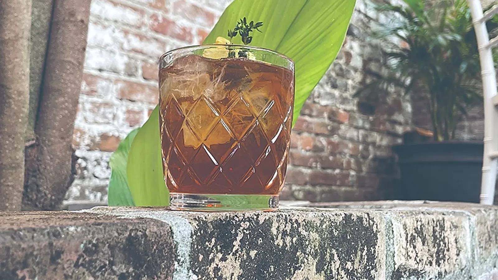a glass of liquid with a leaf on top of it