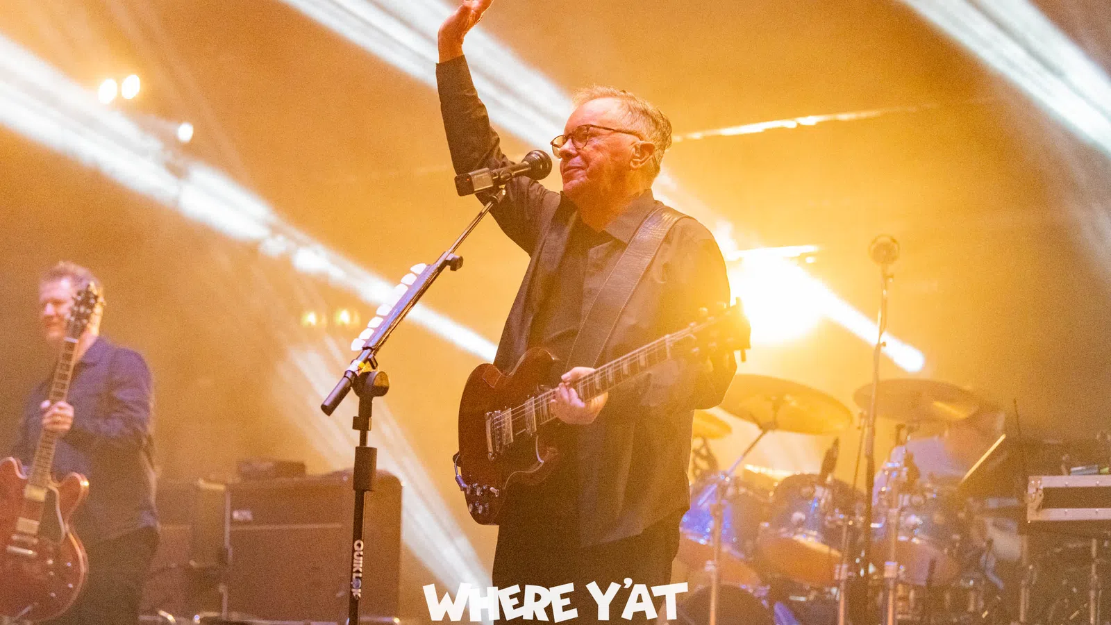 a person playing a guitar on a stage with a microphone