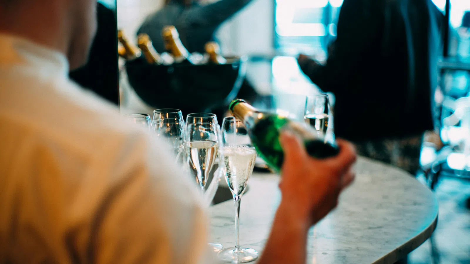 a person pouring wine into glasses