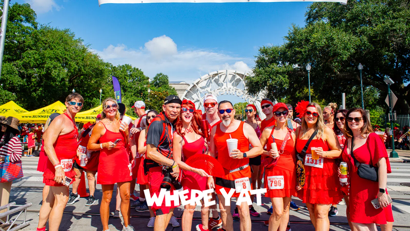 Group of people dressed in red at the NOH3 Red Dress Run start/finish line outdoors on a sunny day.