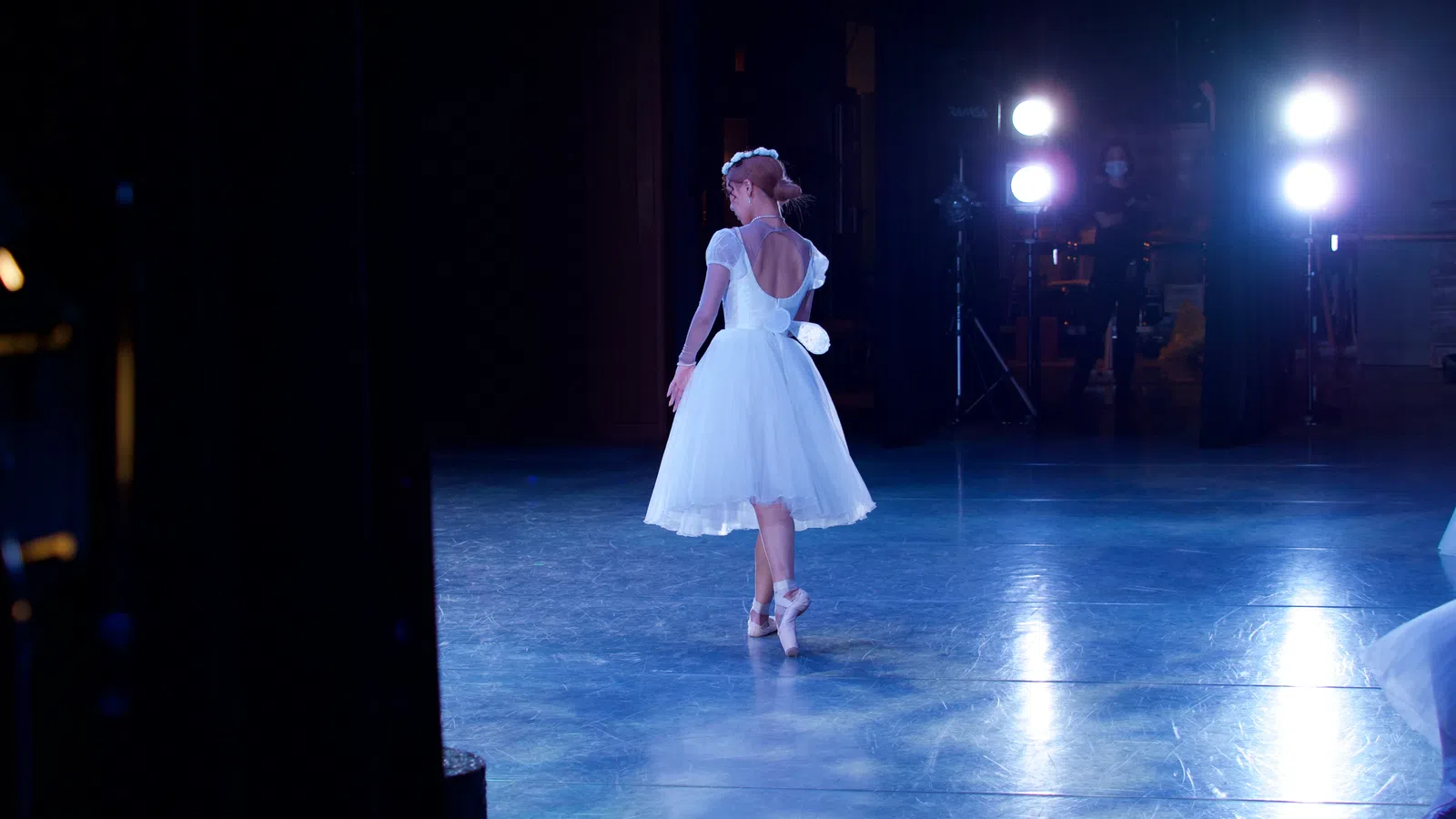 a man wearing a white dress and dancing on a stage