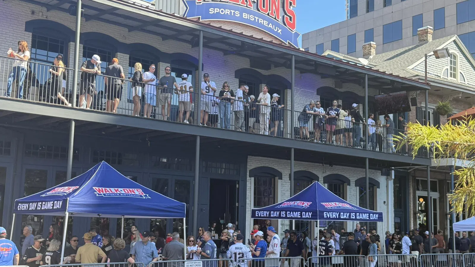 Crowd gathered outside Walk-On's Sports Bistreaux with tents reading Every Day Is Game Day on a sunny day