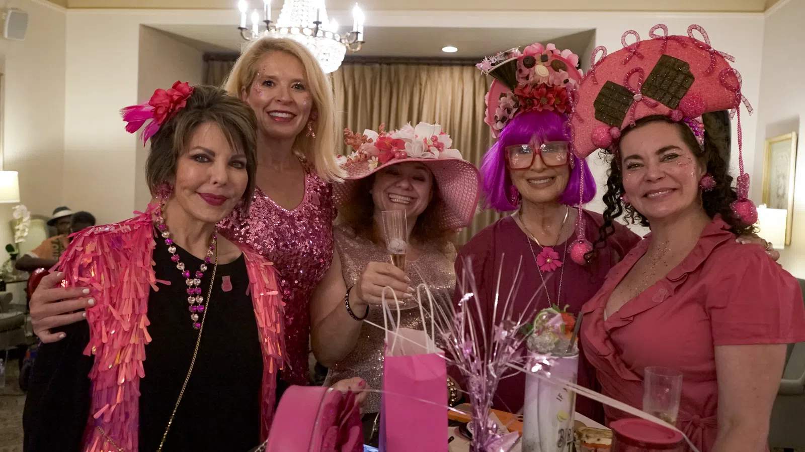 a group of women wearing pink and white hats and posing for a photo