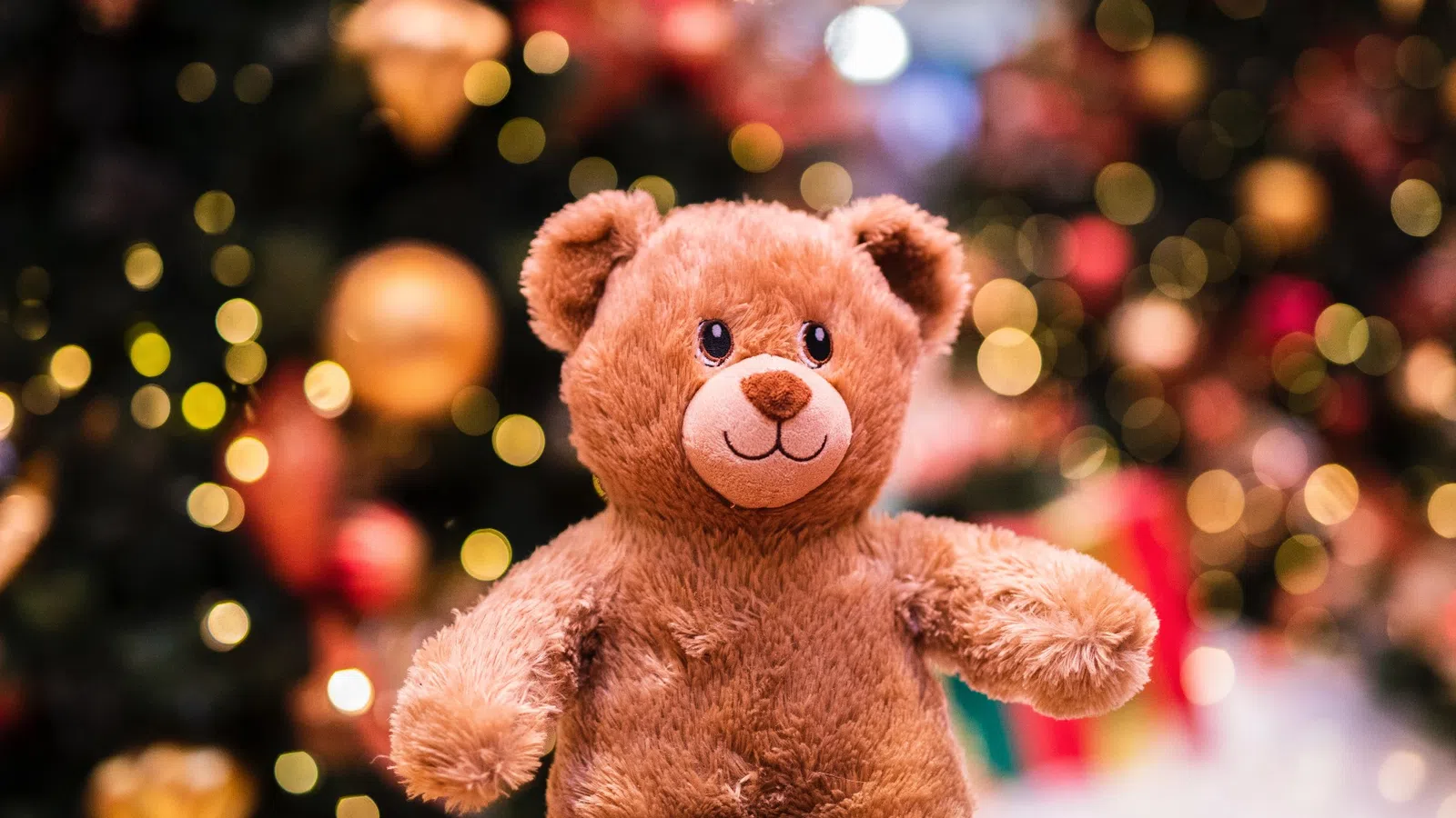 a stuffed bear in front of a christmas tree