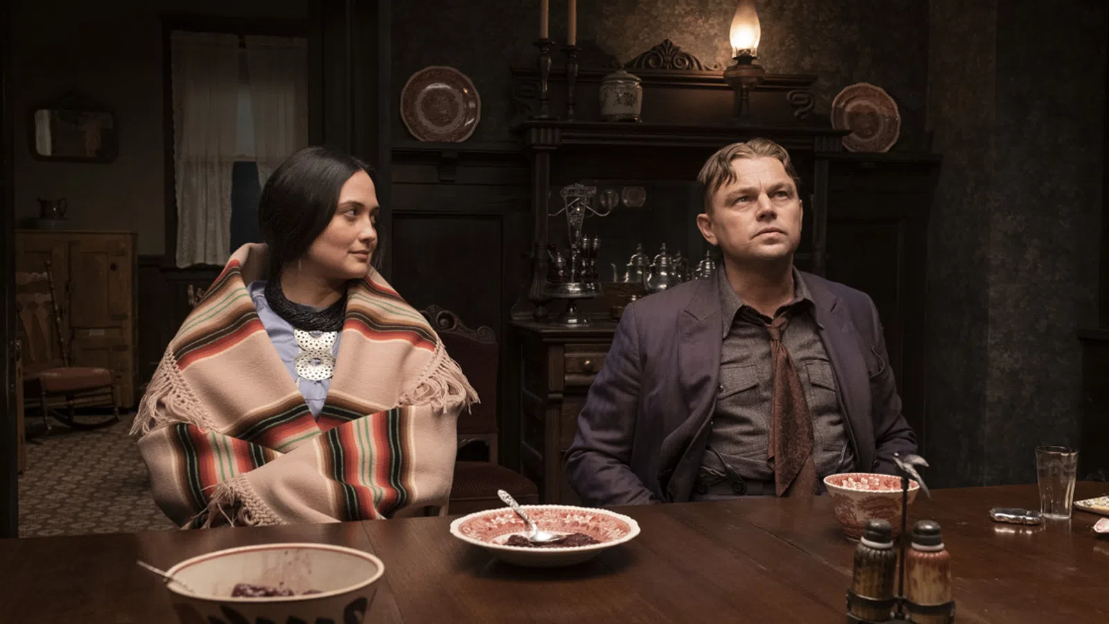 Leonardo DiCaprio, Lily Gladstone sitting at a table with food