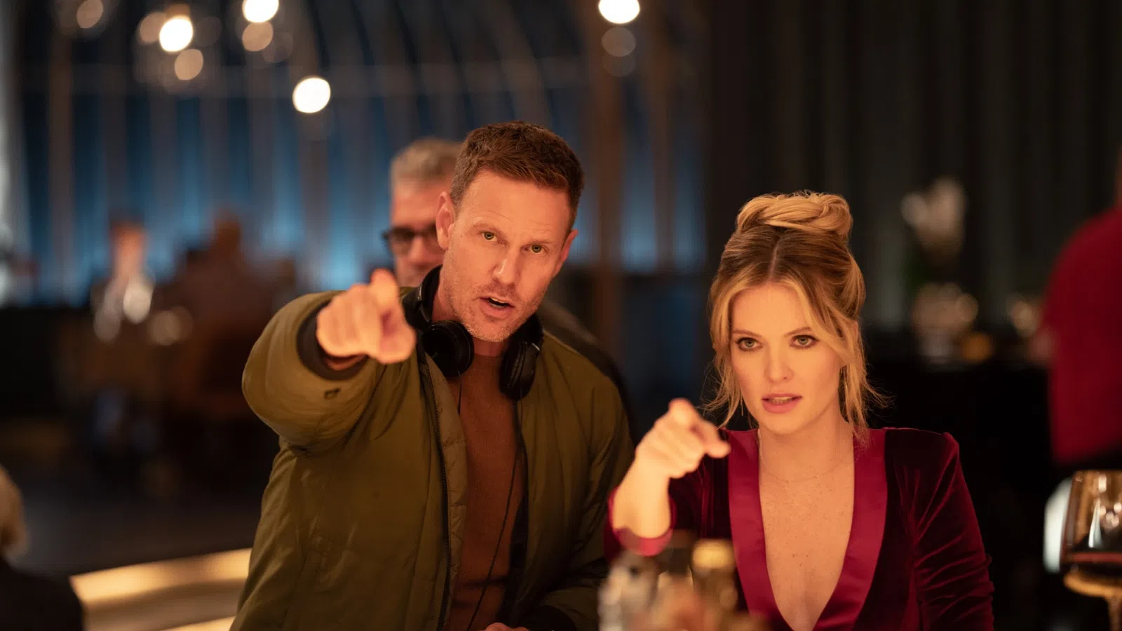 Filmmaker and actress discussing a scene at a stylish bar with drinks and soft lighting.