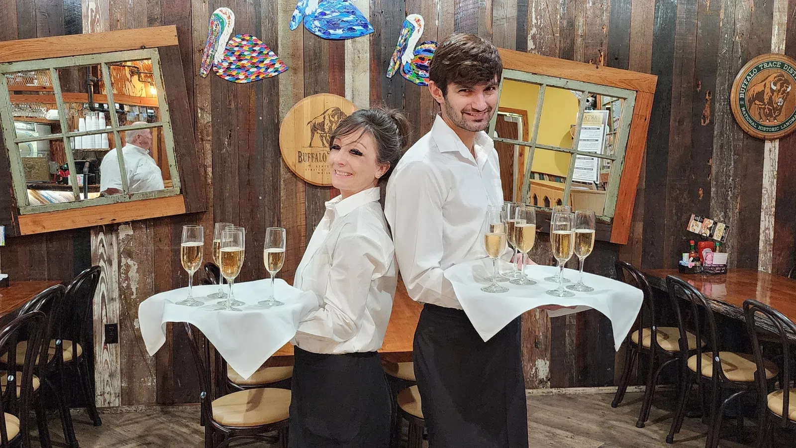 a man and woman standing next to each other at a table with wine glasses