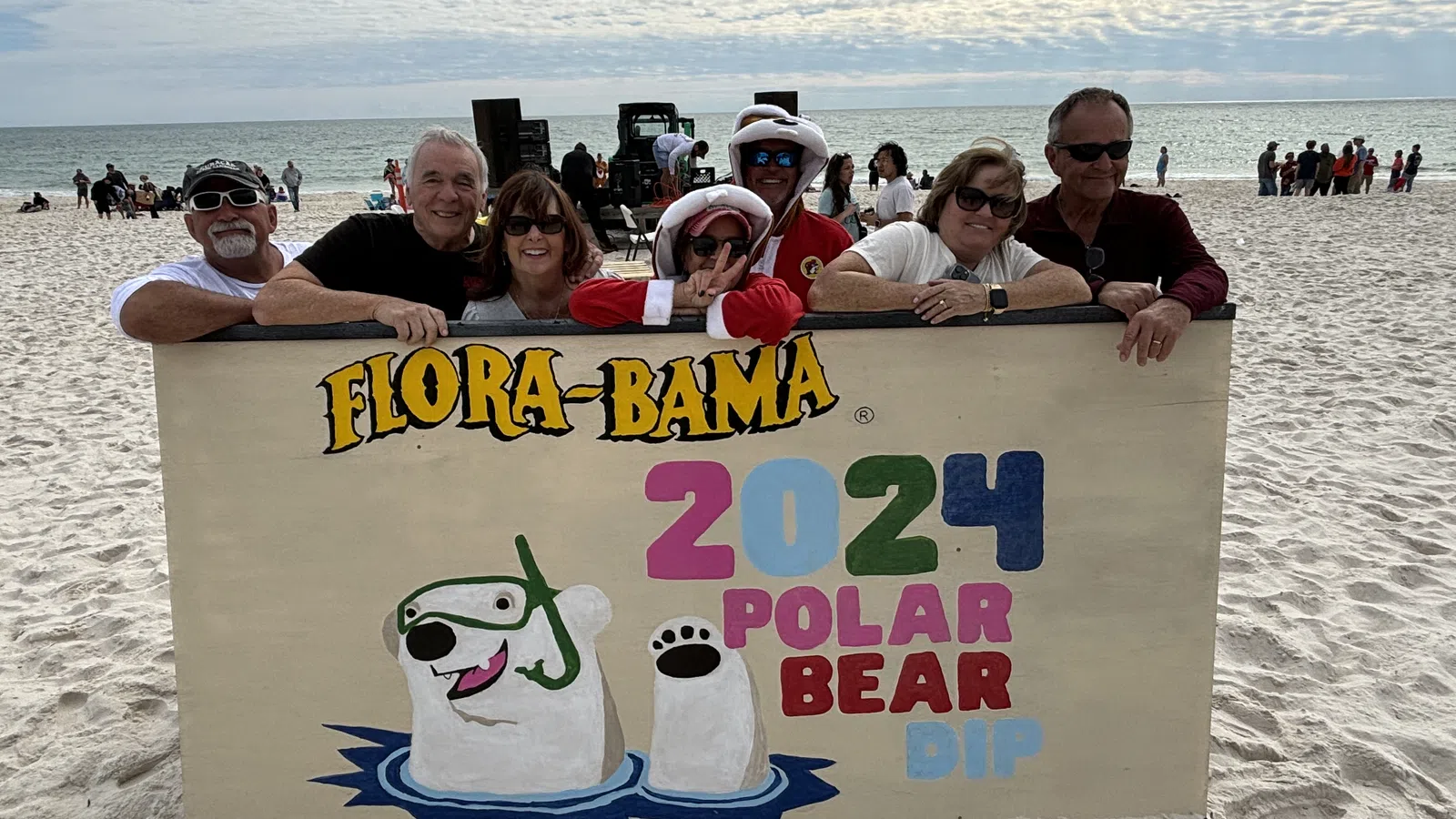 James Bacque et al. on a beach holding a sign